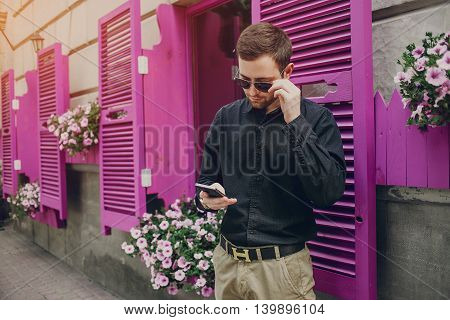 A guy in a nice town, walking, listening to music and taking pictures themselves on the phone