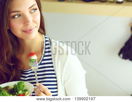Young woman eating salad and holding a mixed salad