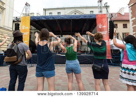 CRACOW POLAND - JULY 24 2016: Pilgrims of World Youth Day sing and dance on the St. Maria Magdalena Square in Cracow. Poland