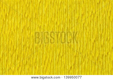 Textural yellow background of wavy corrugated paper close-up. Structural crepe cardboard macro shooting.
