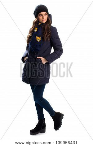 Woman wears navy down jacket. Cap and scarf with print. Warm boots and outerwear. Trendy winter clothes.