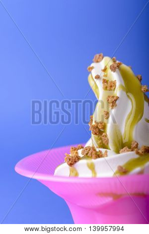 frozen yogurt with green topping and crushed amaretti in pink bowl on blue background