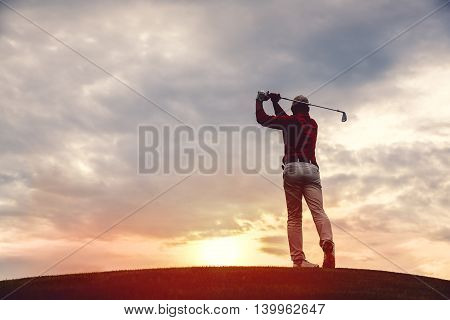 silhouette of man golfer with golf club at sunset. back view