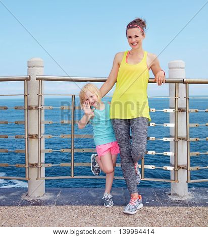 Fitness Mother And Child Standing On Embankment And Handwaving