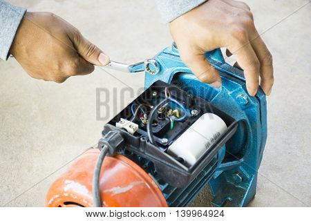 Electric motor  and man working equipment repair on cement floor background. Background motor or equipment.
