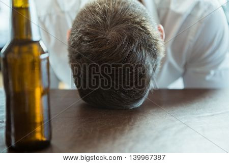 Depressed man with head down on a bar counter at restaurant