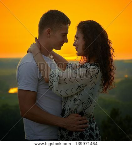 romantic couple at sunset on bright yellow sky background, love tenderness concept, young adult people