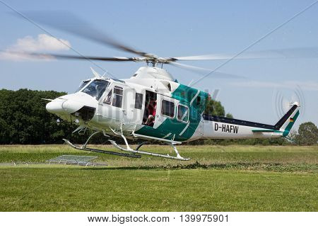 AHLEN GERMANY - JUN 5 2016: Close up view of a Bell 412SP helicopter kicking up grass while landing