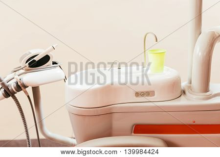Dental chair components: ceramic spittoon water filler and assistant tool rack in a modern dentist office.