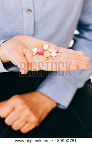 Suicidal intentions of a unknown person holding colored pills in hand