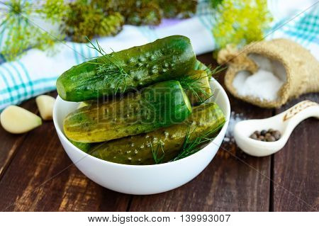 Salted cucumbers. Spices and herbs for making pickles of the wooden background