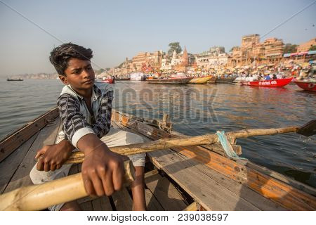 VARANASI, INDIA - MAR 26, 2018: Boatmen on a boat glides through water on Ganges river along shore of Varanasi. According to legends, Varanasi was founded by God Shiva about 5000 years ago.