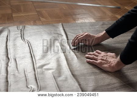 Closeup Of Carpenters Hands Removing Air From Self-adhesive Film