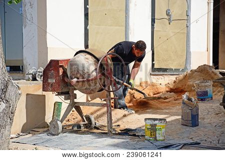 Albufeira, Portugal - June 10, 2017 - Builder Shovelling Sand Into A Cement Mixer, Albufeira, Portug