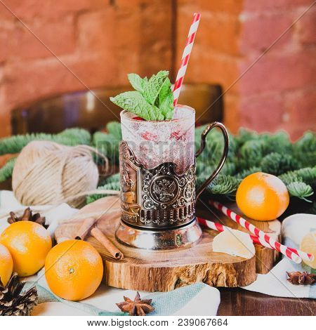 Hot Mulled Wine Drink With Lemon, Apple, Cinnamon, Anise And Other Spices In A Glass Cup Between Fir