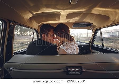 Young Wedding Couple Sitting Smiling Inside Retro Car. Just Married Embrace Is Hugging Inside Car. B