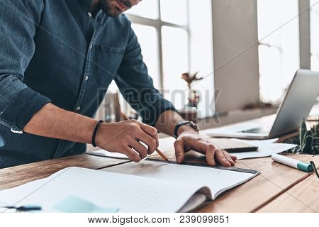 Concentraiting On Project. Close Up Of Young Man Drawing With Ruler And Pencil While Working In The 