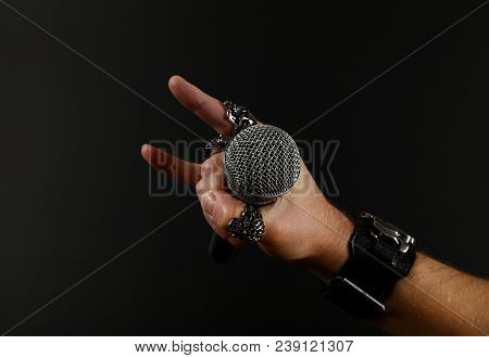 Close Up Man Hand With Metal Rings And Bracelet Showing Devil Horns Rock Gesture Sign, Holding Micro