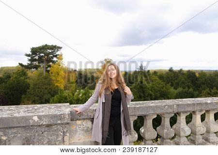Pretty Lady Standing Near Concrete Railing With Green Trees Background. Concept Of Architectural Ele