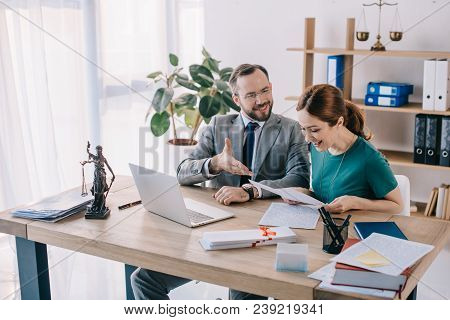 Lawyer And Smiling Client Discussing Contract At Workplace With Laptop In Office