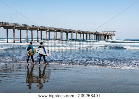 La Jolla, California/usa - April 28, 2018:  Two Male Surfers Carrying Surfboards Heads Out To Sea Ne