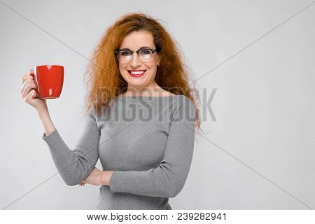 Charming Young Girl With Red Hair. A Young Girl In A Gray Sweater. Young Girl On A Gray Background.
