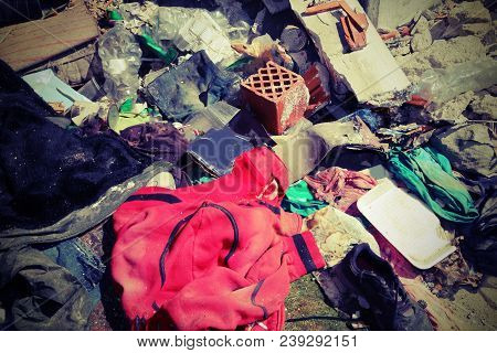 Red Sweatshirt In The Middle Of Rubbish Heaps And Many Rags In A Homeless Camp With Vintage Effect