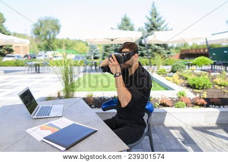 Businessman Enjoying With Virtual Reality Glasses, Working With Laptop And Papers Under Beach Umbrel