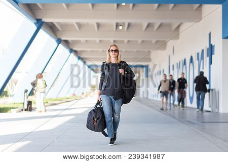 Portrait Of Young Cheerful Female Traveler Wearing Casual Clothes Carrying Heavy Backpack And Luggag