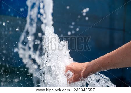 Hand Touch The Fountain. A Stream Of Water From The Fountain Is Touched By Hand.