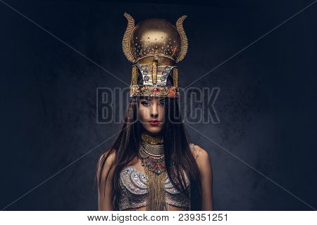 Portrait Of Haughty Egyptian Queen In An Ancient Pharaoh Costume. Isolated On A Dark Background.