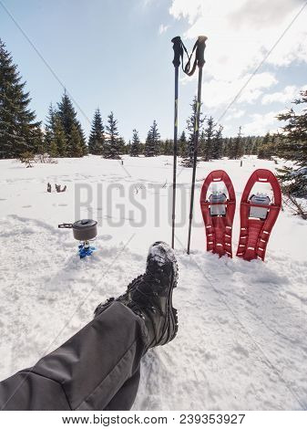 Lunch Time During Winter Trail. Camping On Snow And Cooking. Red Snowshoes And Trekking Poles Stand 