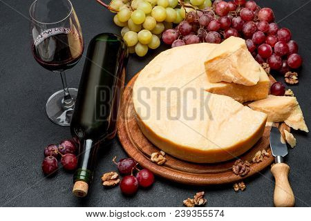 Whole Round Head Parmesan Cheese, Wine And Grapeson Wooden Cutting Board