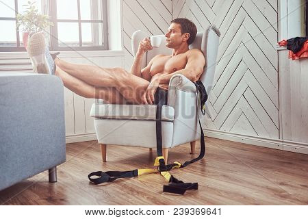Handsome Shirtless Muscular Man Lying On The Chair, Drink Cup Of Tea, Resting After A Hard Workout A
