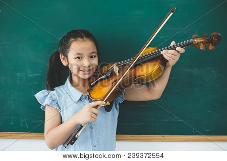 A Littel Cute Girl Playing Violin On Music Class Room At School