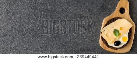 Open  faced cheese sandwich canape or crostini on a wooden serving board  on dark stone background closeup. Top view.