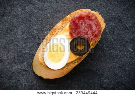 Open faced sandwich canape or crostini on dark stone background closeup. Top view.