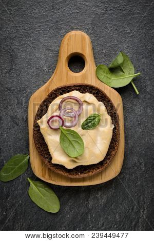 Open faced hummus sandwich canape or crostini on a wooden serving board  on dark stone background closeup. Top view.
