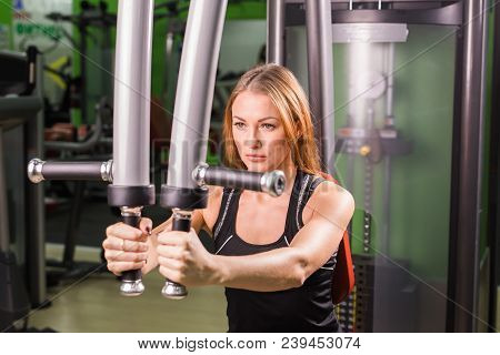 Pretty Caucasian Smiling Woman Is Working Out On Butterfly Machine In Gym