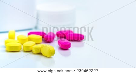 Selective Focus On Yellow Ovoid Rectangular Tablet Pills On Blurred Background Of Pink Tablet Pills 