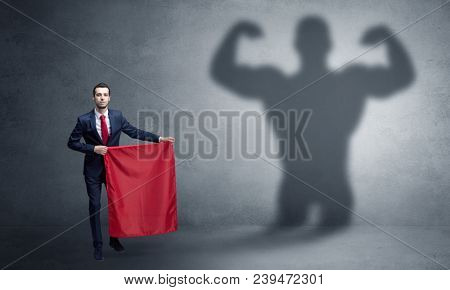 Businessman standing with red cloth on his hand and strong hero shadow on the background