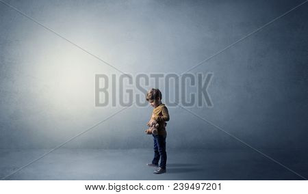 Little waggish kid staying alone in a big empty room with his plush