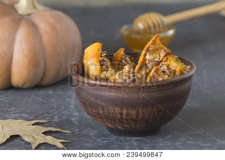 Authentic View Of The Baked Sliced Pumpkin With Honey And Walnuts In A Ceramic Bowl (pial) On A Dark