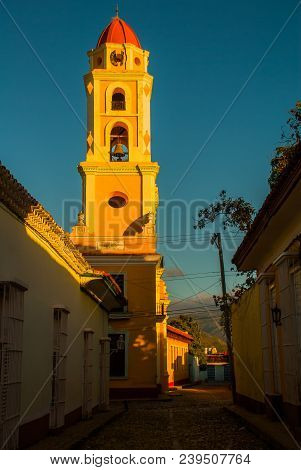 Trinidad, Cuba. The Bell Tower Of San Francisco De Asis Against The Blue Sky. Street In The Center O