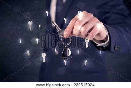 Businessman in suit holding keys with keys graphics around and dark background