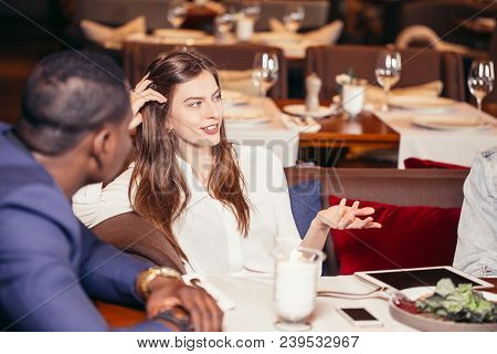 Young Caucasian Attractive Woman In White Blouse Talking And Gesturing With Hands To Afroamerican Me