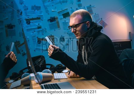 Young Hacker Holding Stolen Credit Card In Dark Room