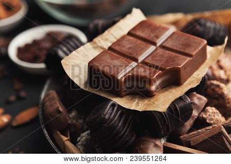 Assortment Of Candies And Milk Chocolate Bar With Piece Bitten Off In Vintage Platter. Various Sweet