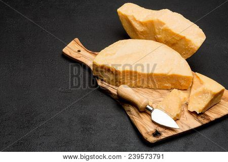 Pieces Of Parmesan Or Parmigiano Hard Cheese And Grapes On Wooden Cutting Board