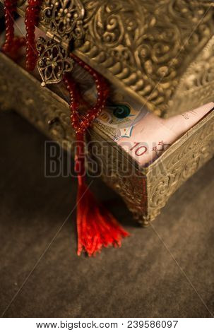 Close up of KWD 10 note and Islamic prayer beads in a vintage trunk. Kuwaiti Dinar - Ramadan charity concept.